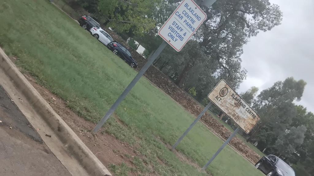a sign on the side of a road next to a speed limit sign at Apartment in Gungahlin
