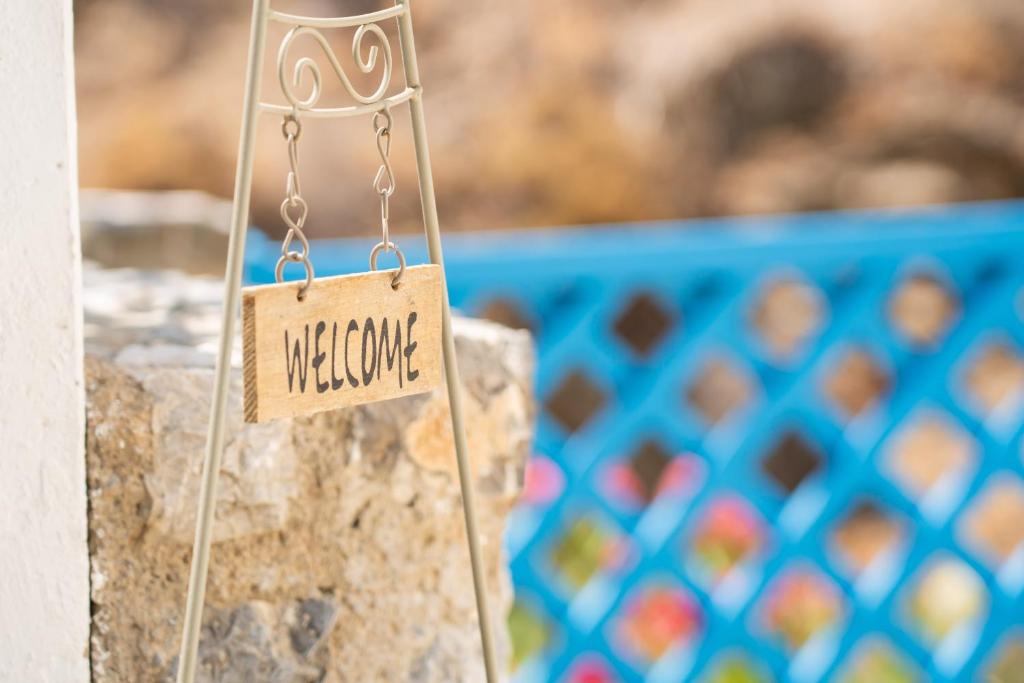a sign that says welcome hanging on a wall at Little Garden in Pera Gyalos
