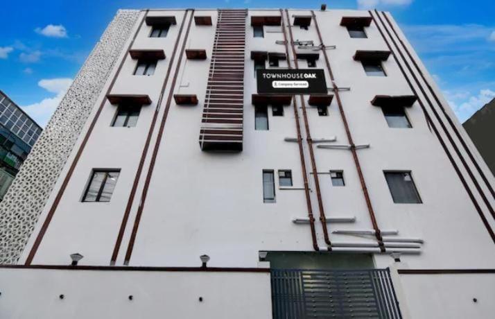 a tall white building with a ladder on it at Creek Row in Kolkata
