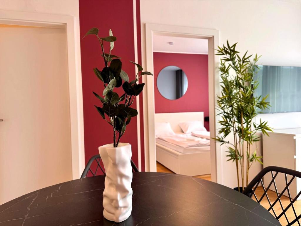a black table with a vase with a plant in it at M2Suites by BestChoice - Messe - Parking - Self-Check-in in Graz