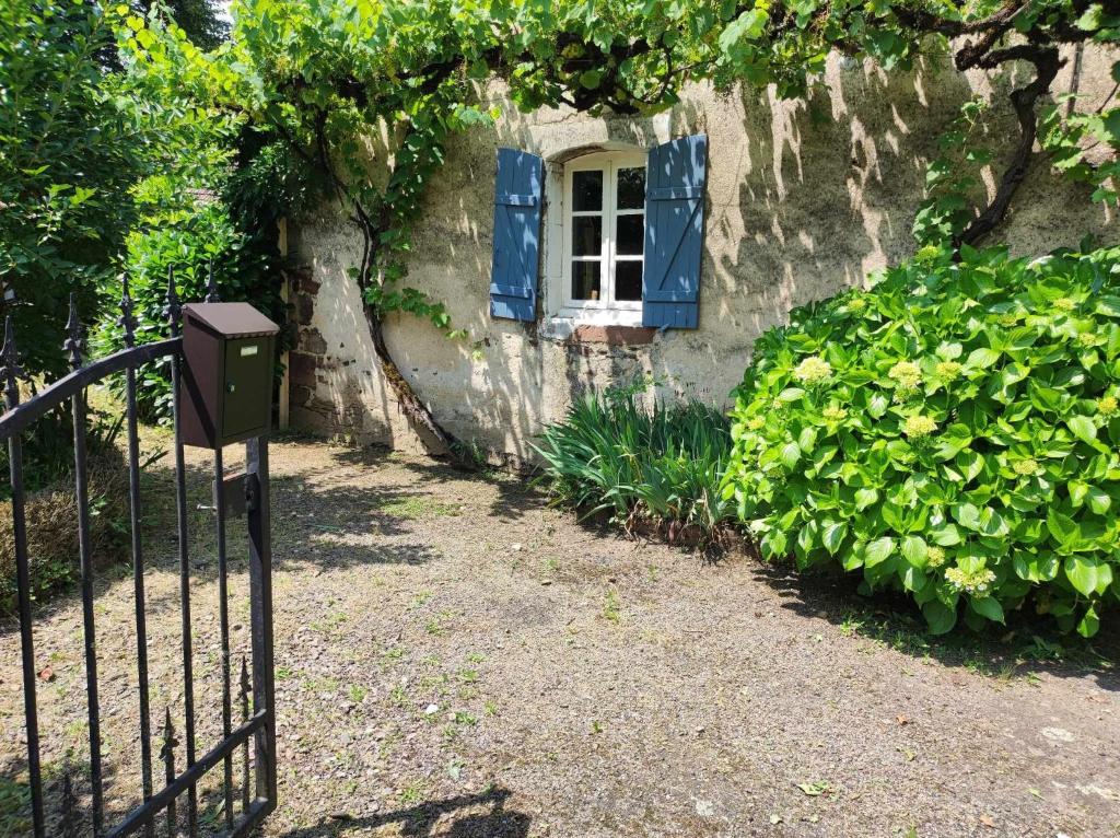 a window with blue shutters on a building with a fence at Gîte Léon, Beynat, Corrèze in Beynat