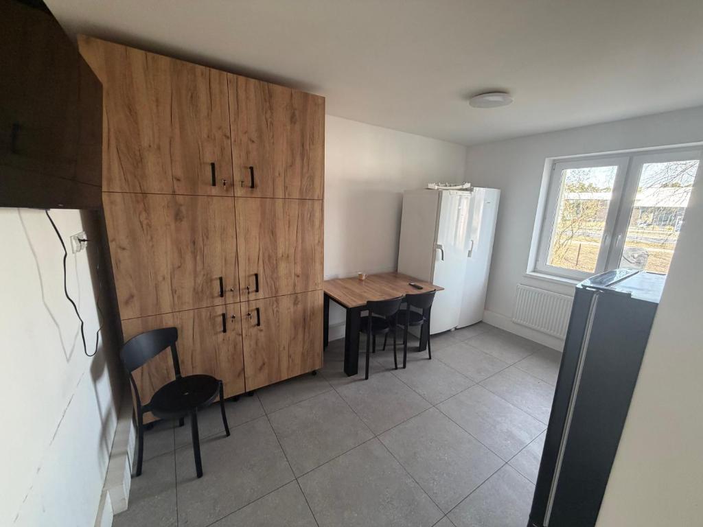 a kitchen with a table and some wooden cabinets at Kwatera pracownicza Leszno in Leszno