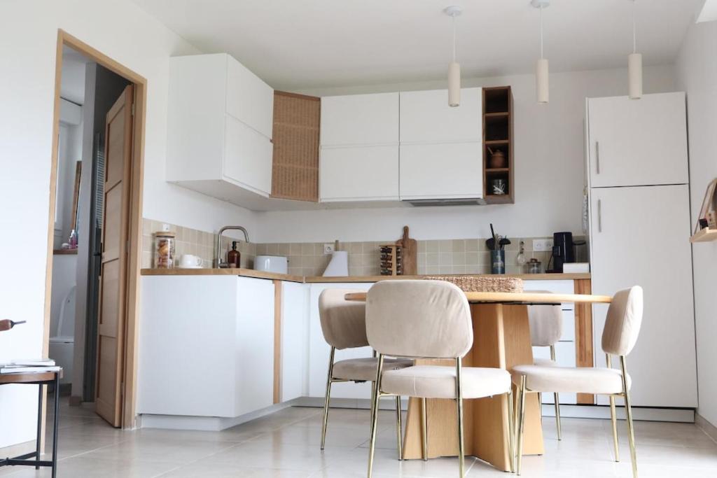 a kitchen with white cabinets and a table and chairs at La parenthèse de la Bouvaque in Abbeville