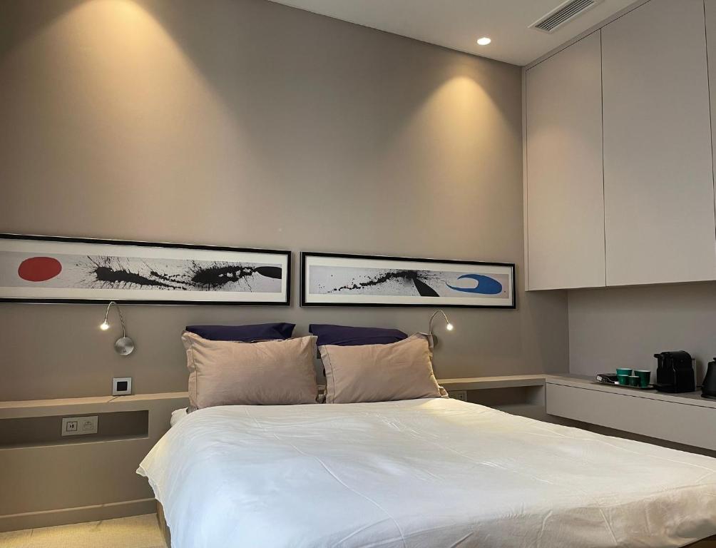 a bedroom with a white bed with three pictures on the wall at Chambre Gounod in Nice