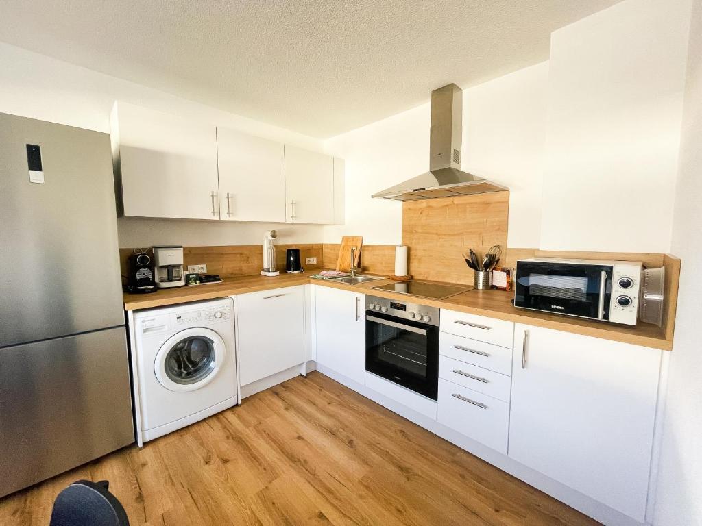 a kitchen with white cabinets and a washer and dryer at Modern Apartment Wissenbach 1 in Eschenburg