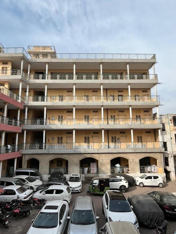 a large building with cars parked in a parking lot at Qaiser Hotel in Lahore