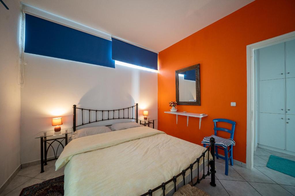 a bedroom with an orange wall with a bed and a chair at Seafarer's Suite by Filos Inc in Galaxidi