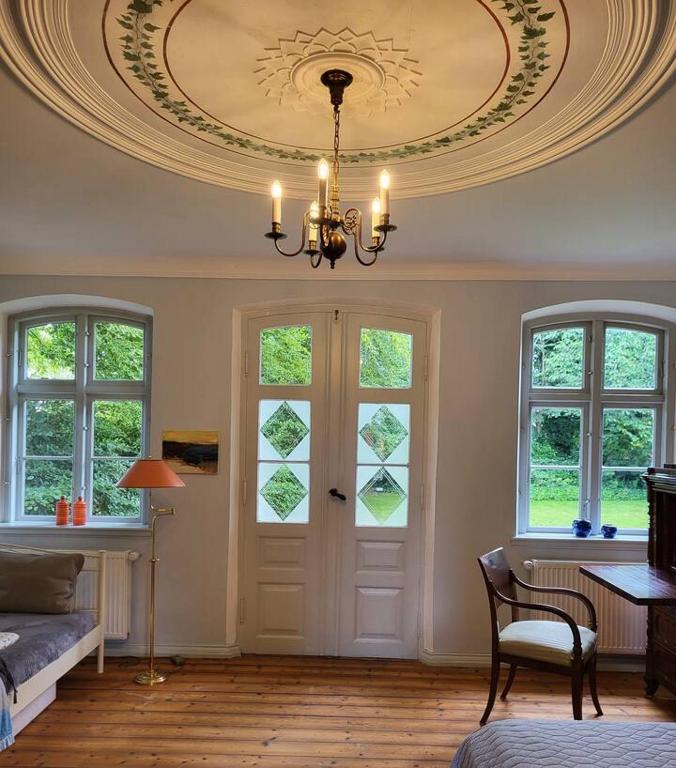 a living room with a chandelier and a door with windows at Inseldomizil Brummers Gaard in Haderslev