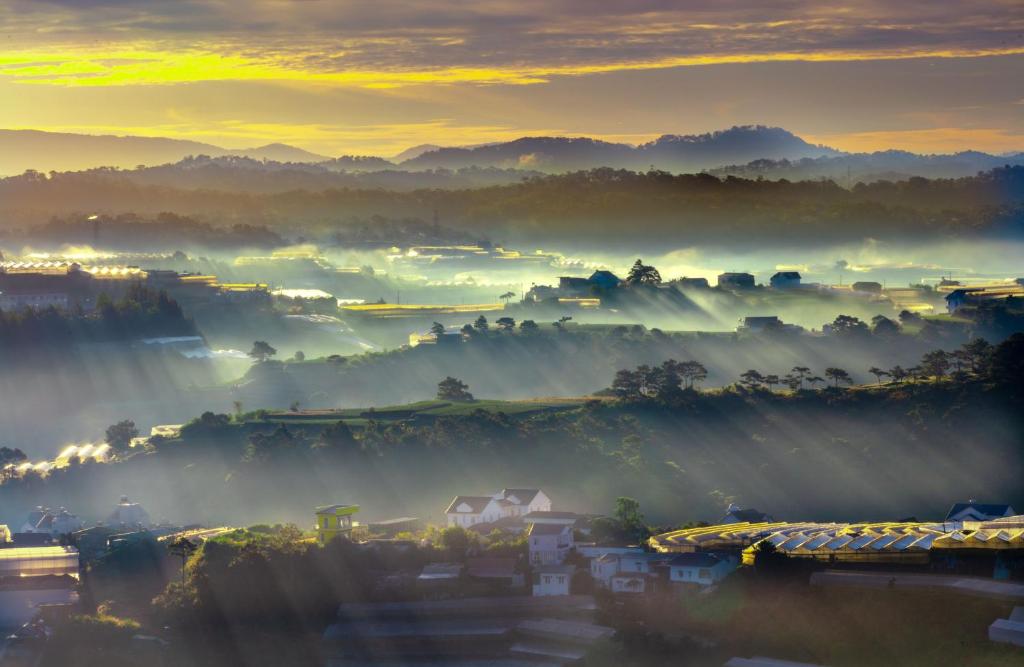 a city in the fog at sunset with houses at holtel Tâm An in Da Lat