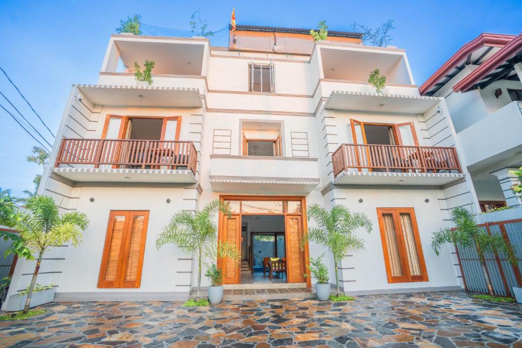a large white house with orange doors and windows at 100Steps Mirissa in Mirissa