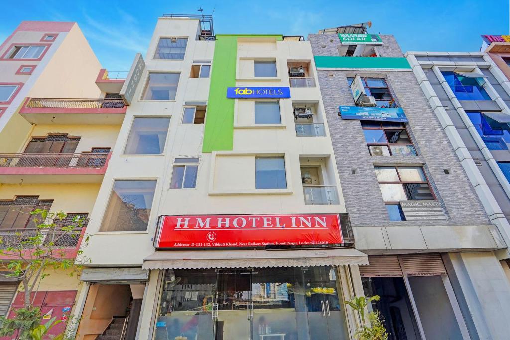 a tall building with a red sign on it at FabHotel HM Inn in Lucknow