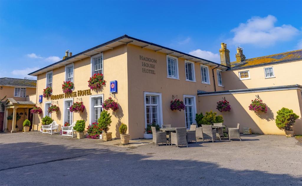 a building with tables and chairs in front of it at Haddon House Hotel in Bridport