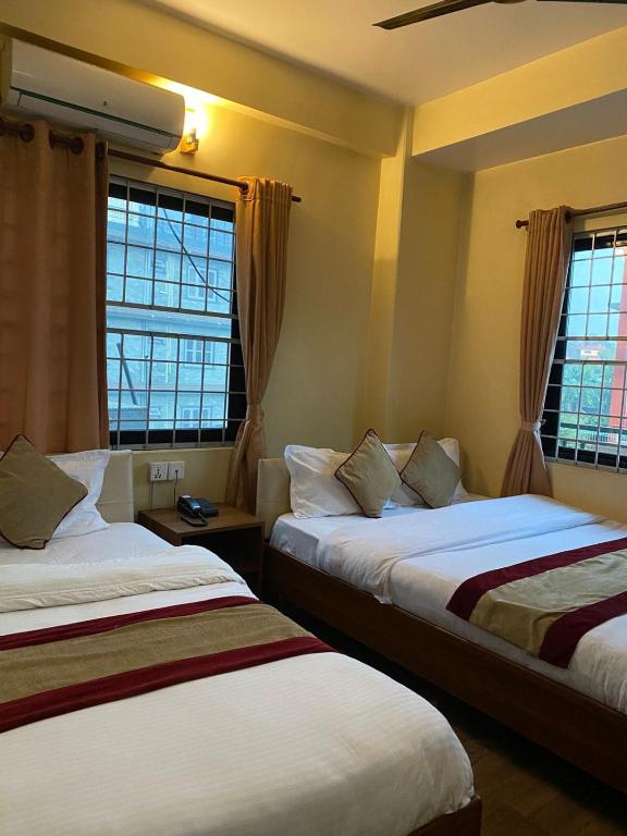 ein Hotelzimmer mit zwei Betten und zwei Fenstern in der Unterkunft Hotel Global Unique in Pokhara