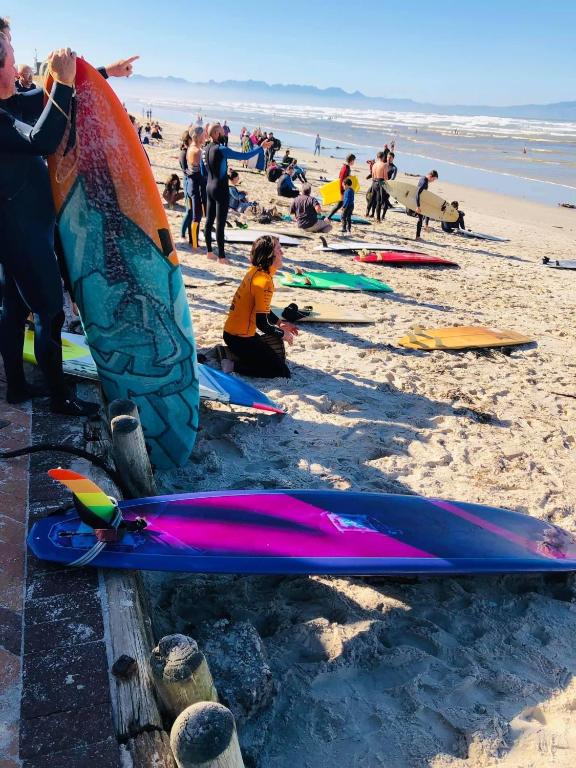 a group of people on the beach with their surfboards at Cape Nomads in Muizenberg