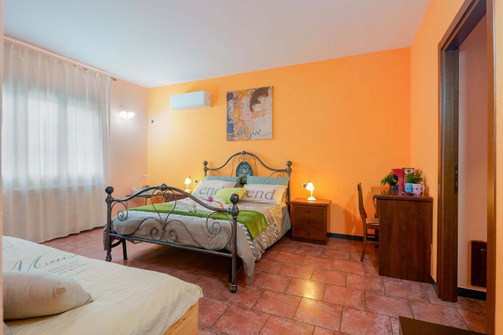 a bedroom with a bed and an orange wall at B&B Gassa d'Amante in Capoterra