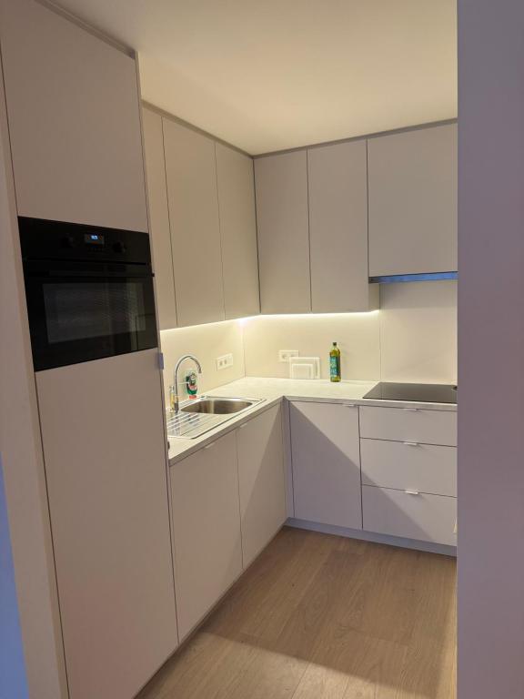 a kitchen with white cabinets and a sink at Cosy Seahouse in Knokke-Heist