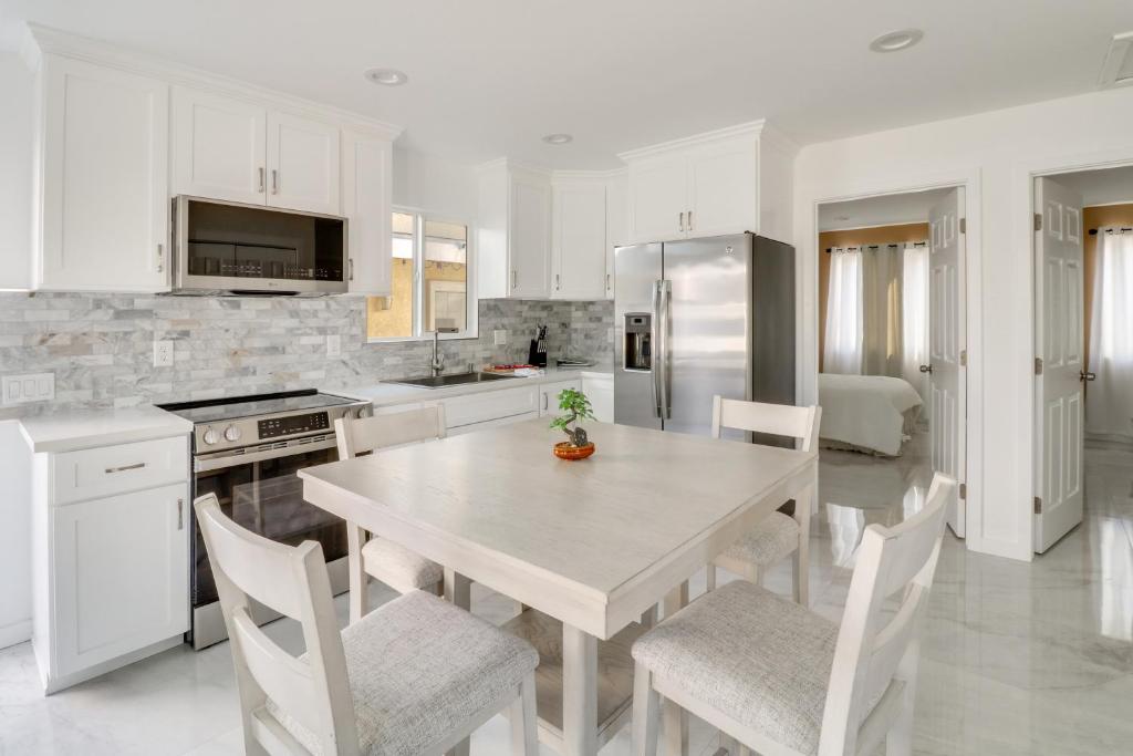a white kitchen with a table and white chairs at 13 Mi to Universal Studios: Renovated Cottage! in Los Angeles