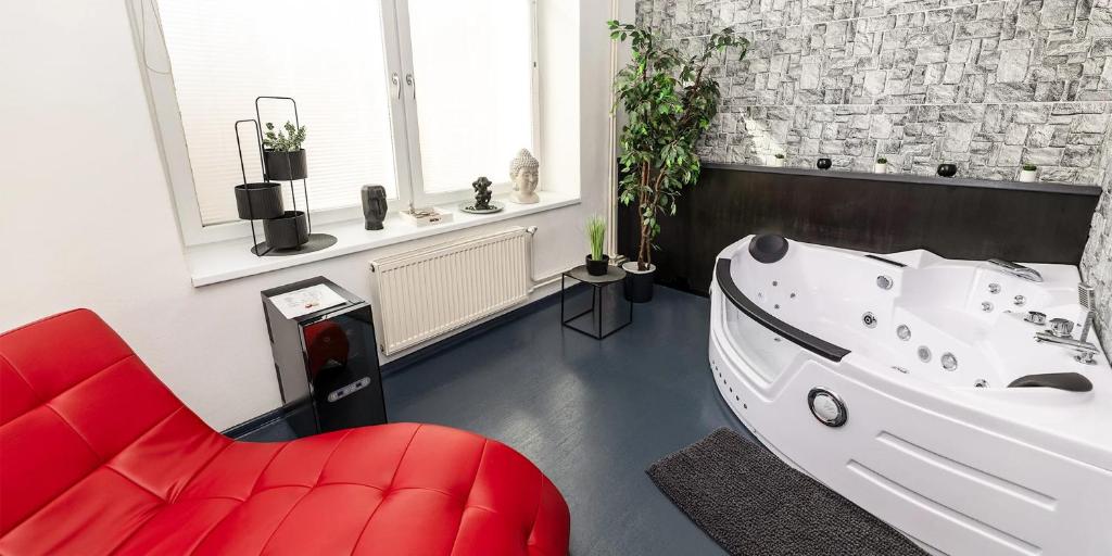 a bathroom with a white tub and a red chair at Wellnes apartmán Leqwell in Uherský Brod