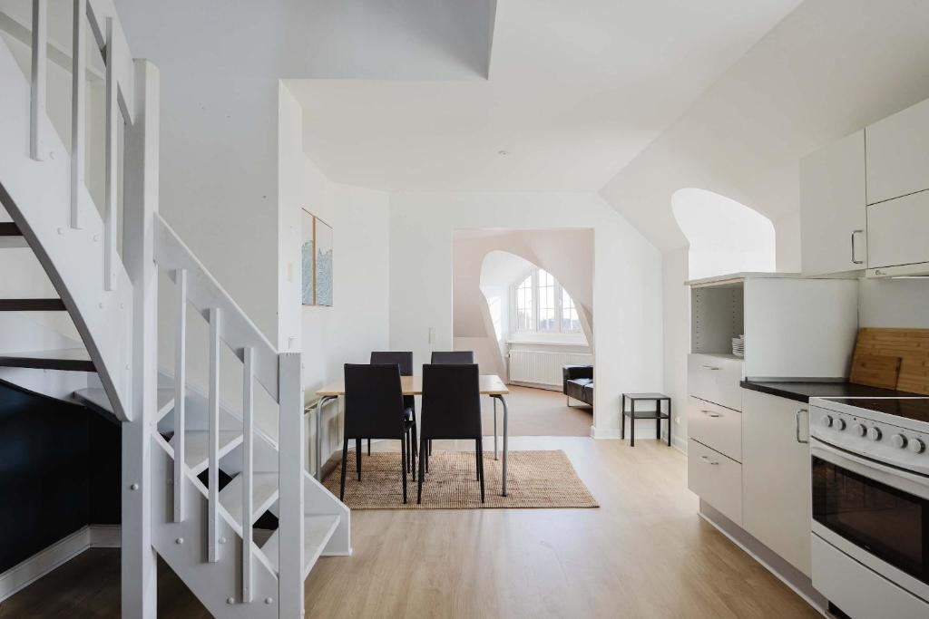 a kitchen and dining room with white cabinets and a table at Odense Doublex Penthouse in Odense