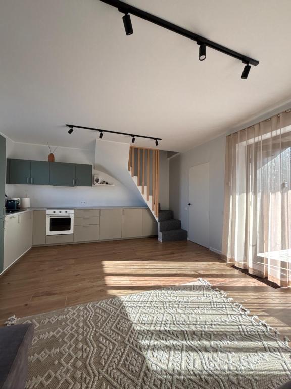 an empty living room with a kitchen and a staircase at Tavo Jūros Namai in Palanga