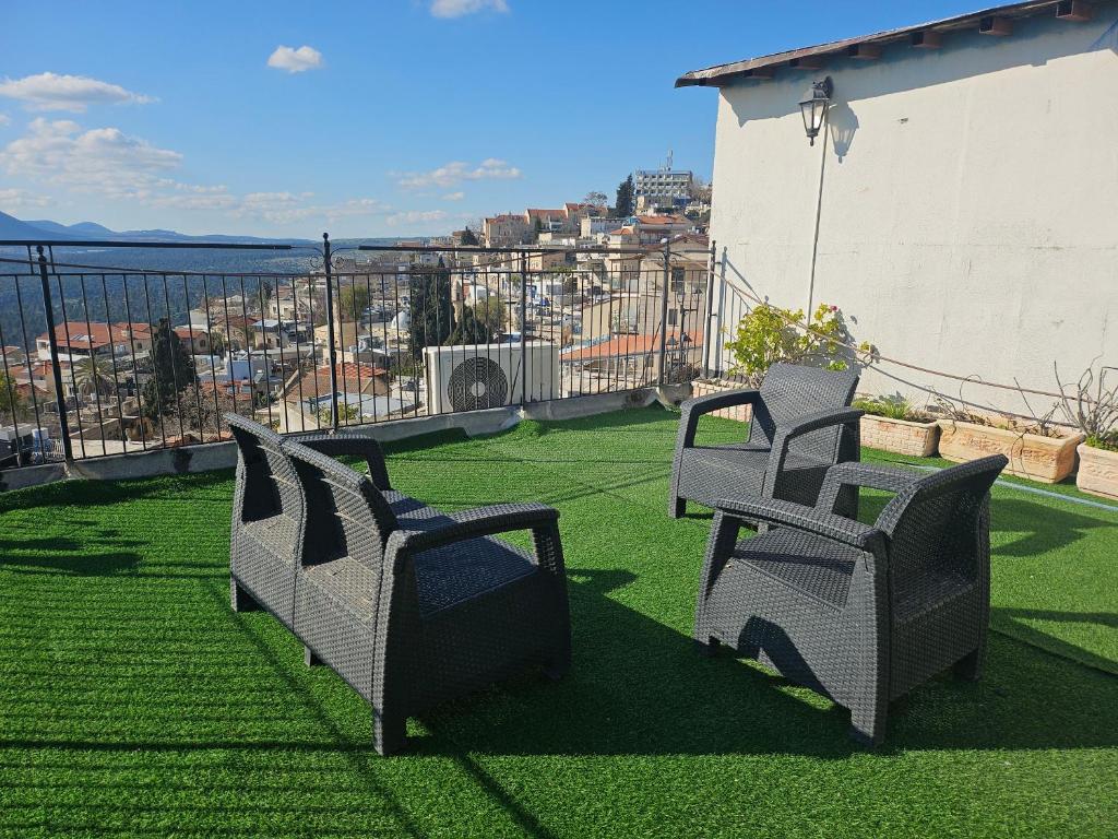 two chairs on a balcony with a view of a city at בית האומן in Safed
