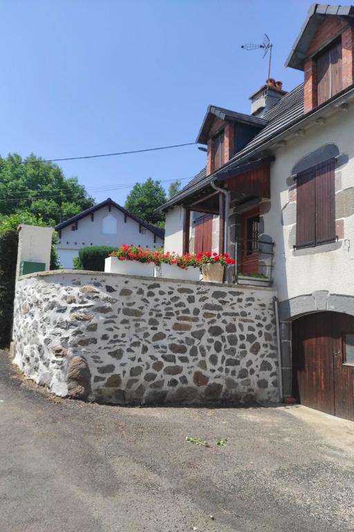 a stone retaining wall in front of a house at Gîte avec jardin pour 6 pers près de Salers Nature & Puy Mary in Le Vigean