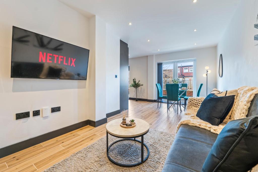 a living room with a couch and a tv on a wall at Modern 2-Bed Apartment 30 mins from Central London in Finchley
