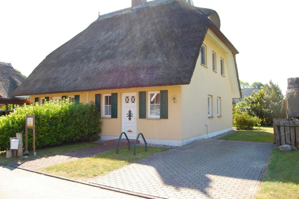 a small yellow house with a thatched roof at Unterm Reetdach in Born