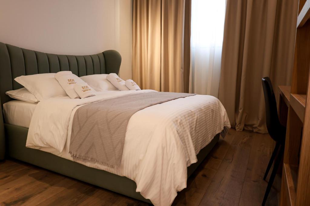 a bedroom with a bed with white sheets and a window at Zoe Boutique Hotel in Durrës