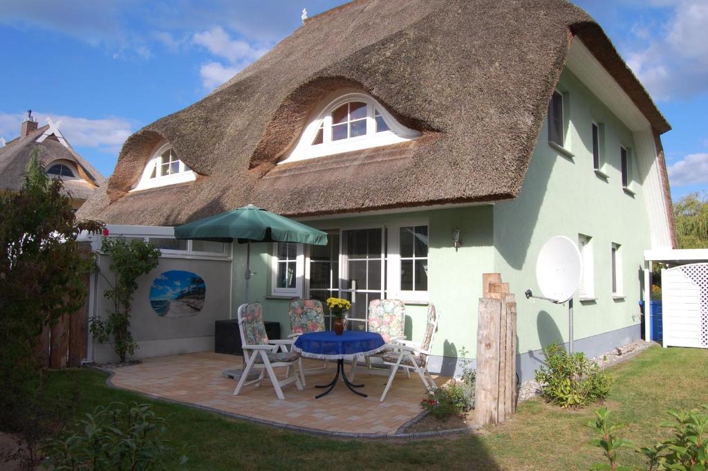 a house with a thatched roof with a patio at Boddenhus in Born
