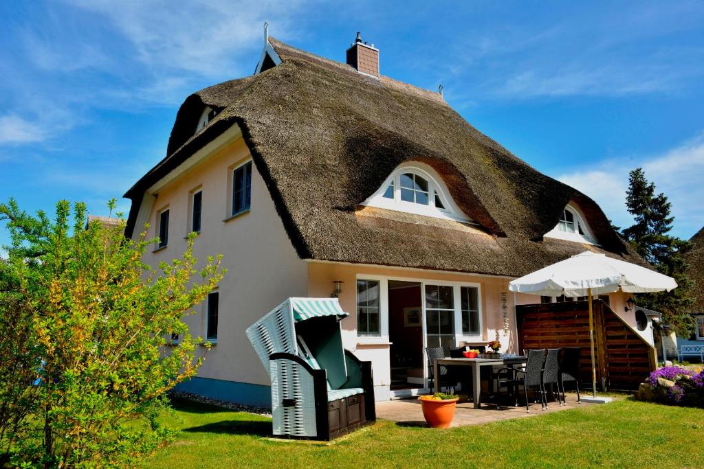 a thatch roof house with a table and chairs at Schipperhus in Born