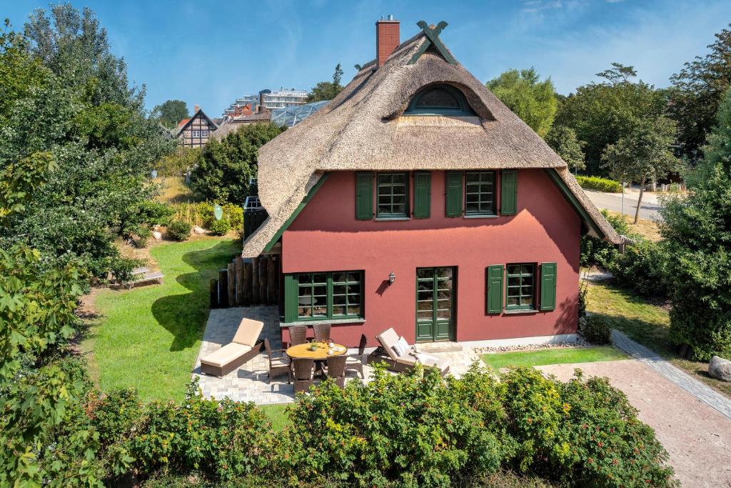 a pink house with a thatched roof with a table at Strandhaus Ahrensh 1 in Ahrenshoop