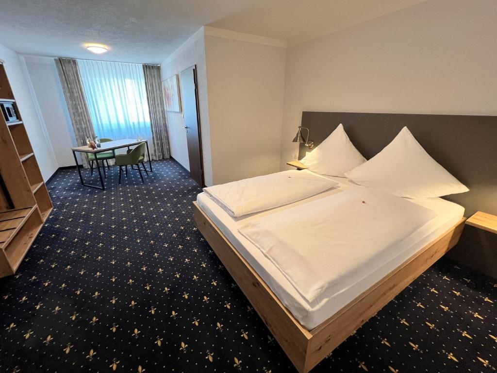 a hotel room with a large bed and a table at stadthotel miya in Bad Mergentheim