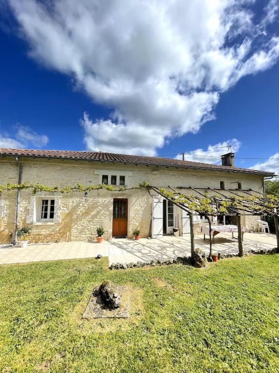 a stone house with a yard in front of it at La maison de La Combe in Parzac