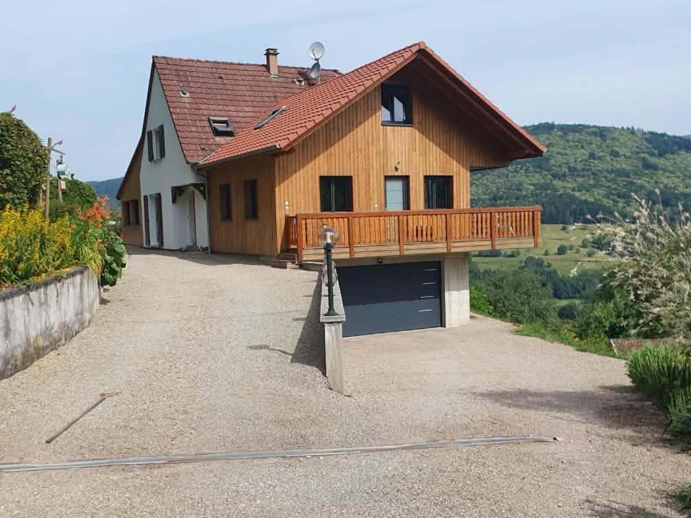 a wooden house with a garage and a driveway at Le Chalet de la belle vue in Fouchy