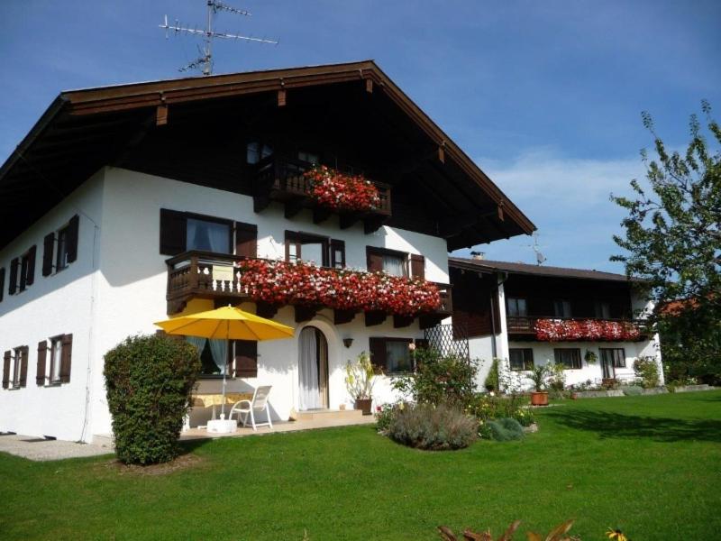 a white building with a balcony and an umbrella at Ferienwohnungen Wennesz in Chieming