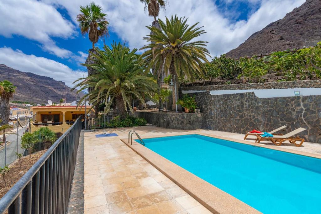 a swimming pool with palm trees and a house at GC0284 El Granero in Mogán