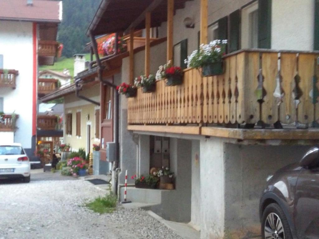 a building with a balcony with flowers on it at Appartamenti dei Maerins in Pozza di Fassa