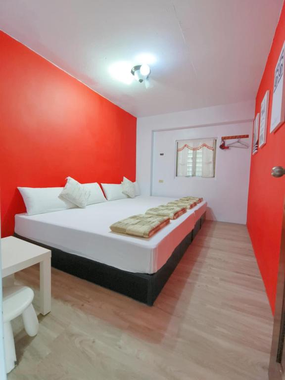 a bedroom with a bed with a red wall at Yabiya home stay in Lanyu