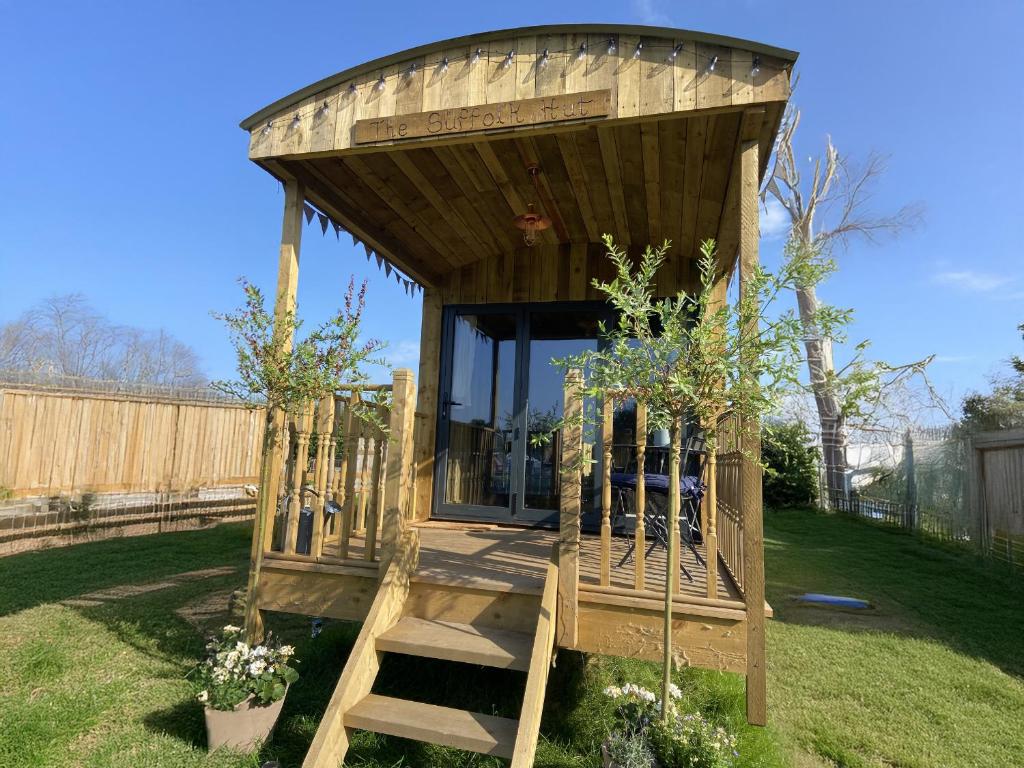 a wooden gazebo with a staircase in a yard at The Suffolk Hut in Knutsford