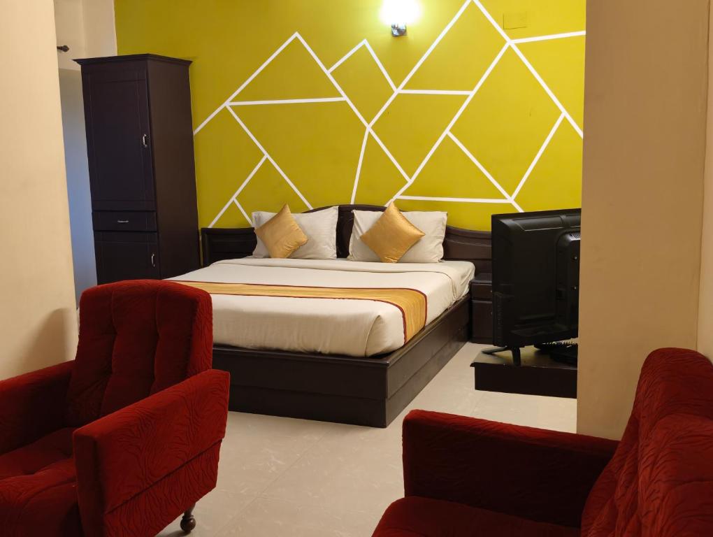 a bedroom with a bed and two chairs and a tv at Hill View Residency in Kalpetta