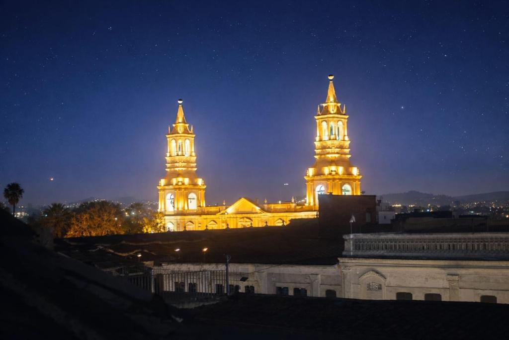 a building with two towers lit up at night at Peter's Hostel in Arequipa