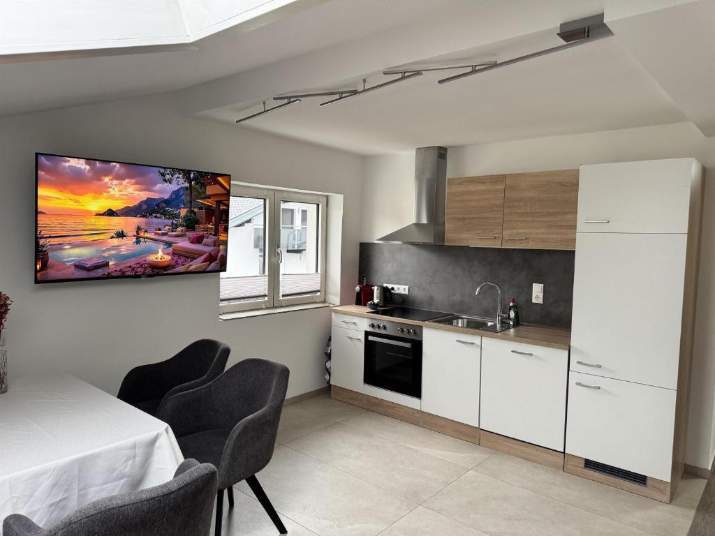 a kitchen with white cabinets and a table with chairs at Tirol Stay in Ebbs