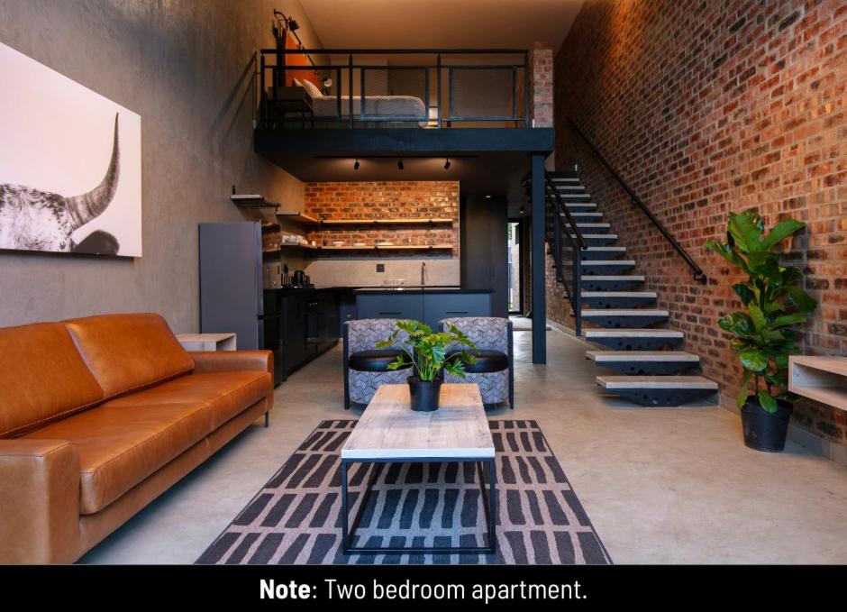 a living room with a couch and a brick wall at Menlyn Lofts in Pretoria