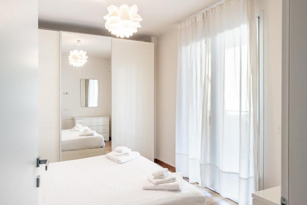 a white bedroom with two beds and a mirror at Gerusalemme's Nest - In the heart of the city in Milan