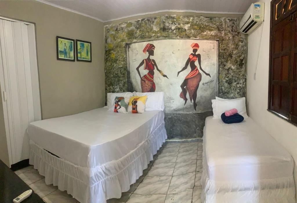 two beds in a room with a painting on the wall at Suite Africana Aracaju in Aracaju