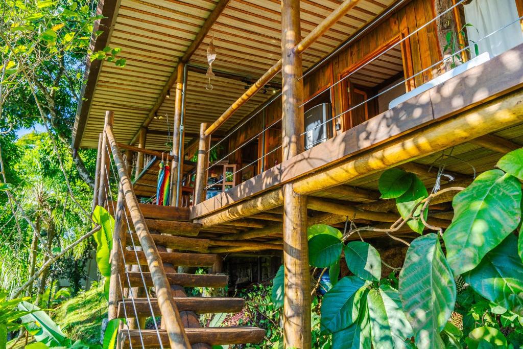 a wooden house with a staircase leading up to it at Casas D'Água Doce - Casa Amora in Ilhabela