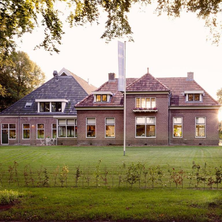 a large brick house with a lawn in front of it at Landhuis Hotel Restaurant Rikus in Eext