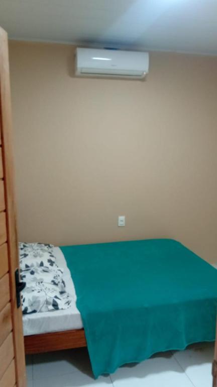 a small bedroom with a bed with a green blanket at Espaço Mãe Cecília in Paripueira