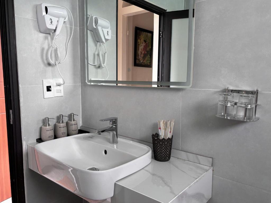 a bathroom with a white sink and a mirror at Long Bình Hotel in Dong Hoi